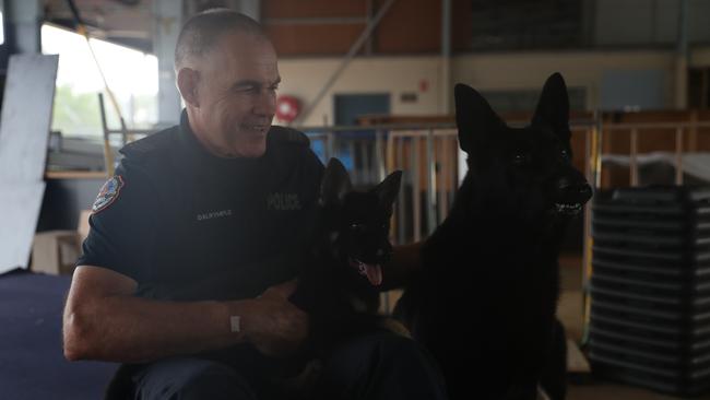 NT Police Dog Operations Unit Senior Constable Steven Dalrymple with the squads newest recruits, Axe and Jax. Constable Dalrymple's canine partner Drax is the puppy's father.