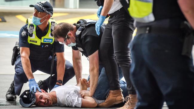 An anti-lockdown protester is held at a rally near Melbourne’s Shrine of Remembrance. Picture: Jake Nowakowski