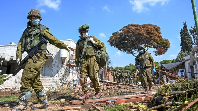 IDF soldiers point to the body of a Hamas militant who was killed days earlier after attacking this kibbutz near the border with Gaza.