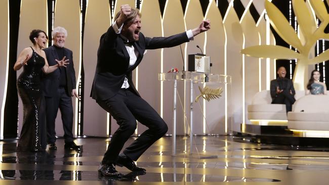 Director Ruben Ostlund celebrates winning the Palme d'Or, with Juliette Binoche and Pedro Almodovar behind him. Picture: AP.