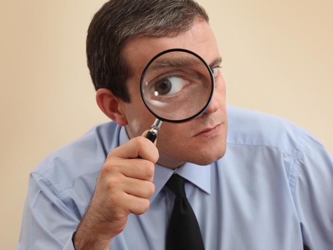 Businessman looking through magnifying glass. Focus on his hand and magnifying glass. tax generic money