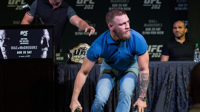 Conor McGregor grabs two cans during the chaotic press conference for UFC 202.