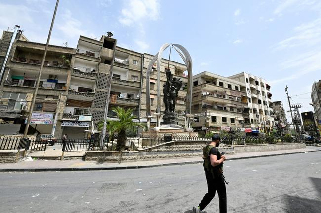 An armed man walks through the mostly Druze and Christian Damascus suburb of Jaramana, which came under attack by Islamists this week