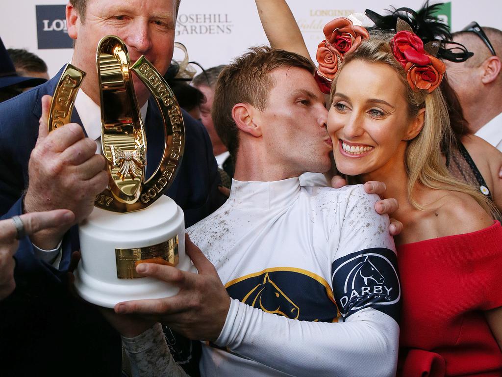 Jockey Ben Melham kisses his partner Karlie Dales as he and trainer Gary Portelli (left) hold the Golden Slipper trophy.