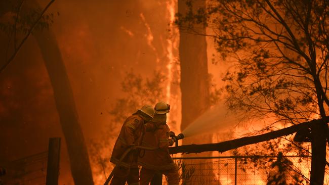 RFS volunteers and NSW Fire and Rescue officers protect a home on Wheelbarrow Ridge Road caught in the Gospers Mountain fire near Colo Heights, northwest of Sydney, in November last year. Picture: AAP