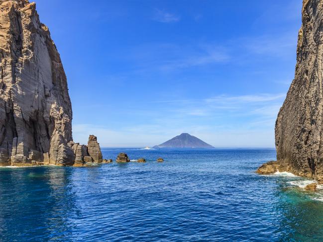 The island of Stromboli seen among the rocks off the island of Panarea in the Aeolian Archipelago off Sicily.