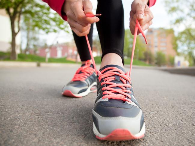 Sporty woman tying shoelace on running shoes before practice. Female athlete preparing for jogging outdoors. Runner getting ready for training. Sport active lifestyle concept. Close-upGeneric, istock