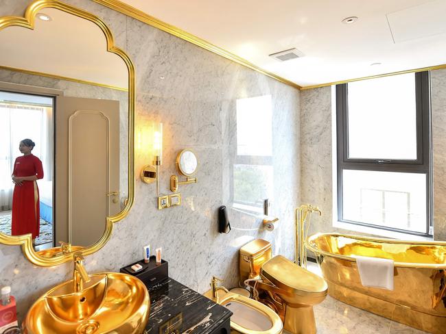 A staff member poses for a photograph inside the 1,000 USD per night executive two bedroom suite of the newly-inaugurated Dolce Hanoi Golden Lake hotel, the world's first gold-plated hotel, in Hanoi on July 2, 2020. (Photo by Manan VATSYAYANA / AFP)