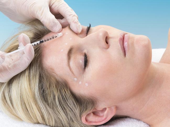 Woman lying down receiving botox injection in her forehead.