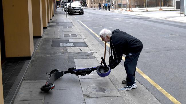 eScooters and eBikes city hazard. John Mete 80 from Victoria, tries to pick up an eScooter that was blocking the footpath pushing him on the road. The ebike was too heavy for him and when the eScooter alarm went off so he stopped moving it. Picture: Tricia Watkinson