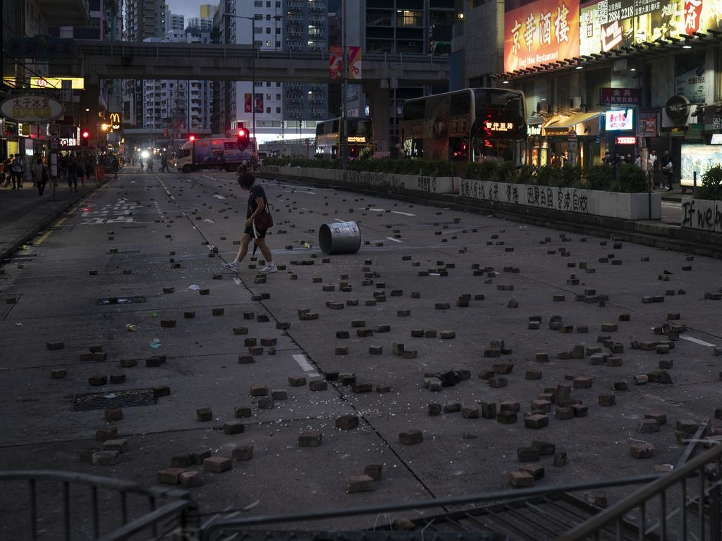 A woman walks past bricks thrown by protesters. Picture: AP