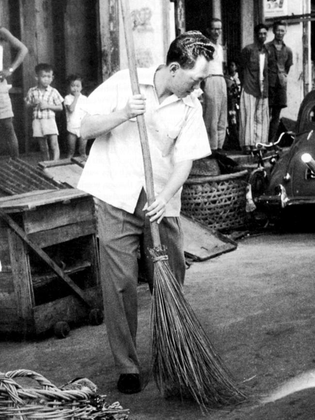 Prime Minister Lee Kuan Yew takes to the broom and sweeps the street to set an example of cleaniness in newly independent Singapore in anundated photo from his memoirs.