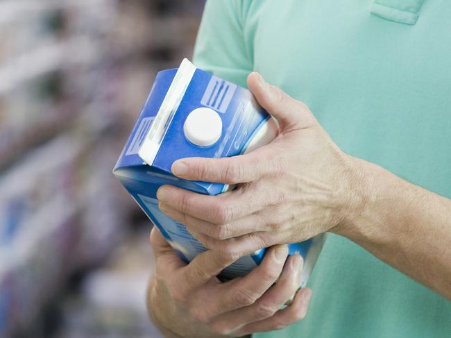 Man reading milk label in grocery store