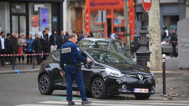 A police officer stands by a Renault Clio with Belgian license plates in Paris, Tuesday, Nov.17, 2015 and that could be linked to Friday's attacks. The car was discovered near the commuter train line that links to France’s national stadium, which was a site targeted by 3 suicide bombers. (AP Photo/Thibault Camus)