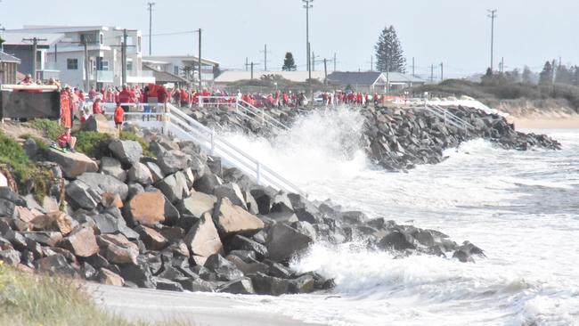 More than 2000 protesters dressed in red and formed a line along the edge of Stockton Beach from the caravan park. Supplied.