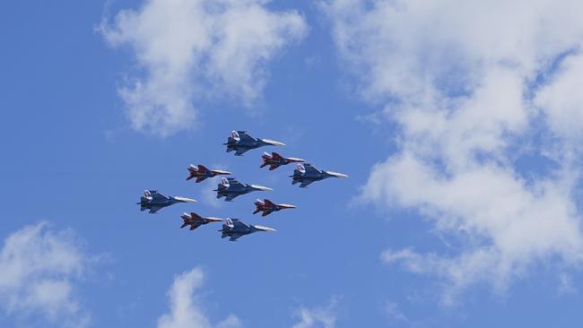 Russian Sukhoi Su-30SM jet fighters, centre, of The Russian Knights aerobatic team and Mikoyan MiG-29 jet fighters of The Swifts aerobatic team fly over Red Square