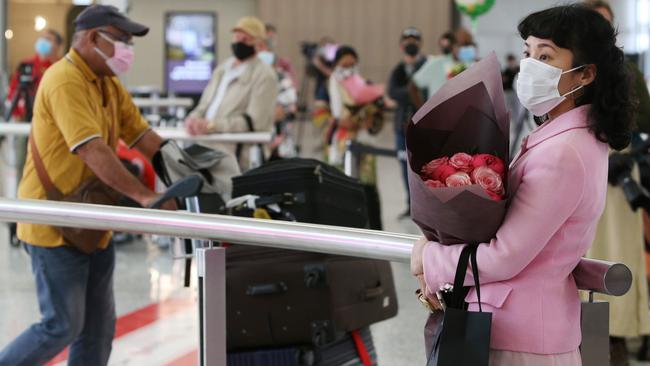 A woman holds flowers as she awaits the arrival of family on Monday. Picture: Getty Images