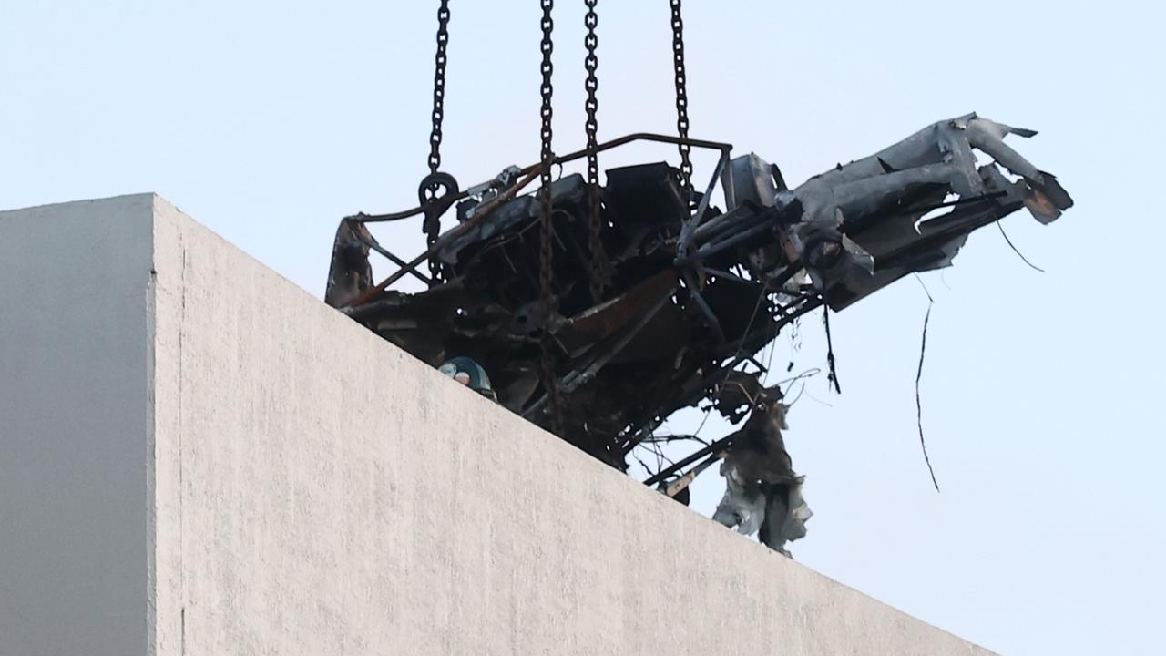 A large crane lifts the wreckage of a Robinson R44 helicopter off the roof top of the Double Tree Hilton hotel into a skip bin, before lowering it to the Cairns Esplanade. The chopper was stolen from Nautilus Aviation and crashed onto the roof at about 1:50am on Monday. Picture: Brendan Radke