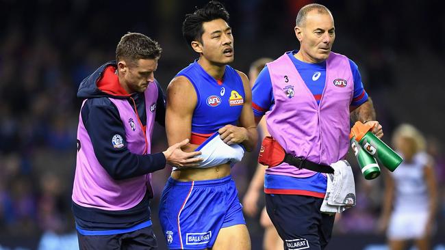 Lin Jong is helped from the ground after injuring his shoulder.