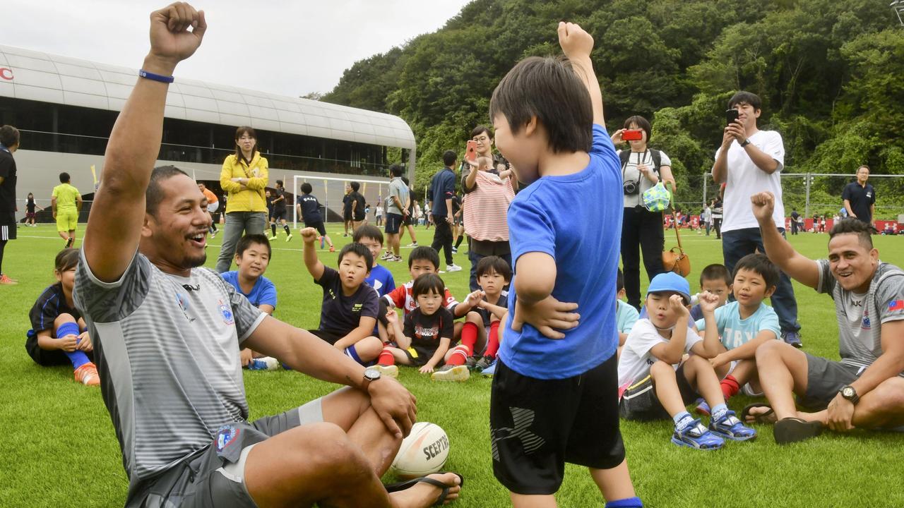 Samoa rugby team members react with children at a rugby clinic in Iwaki, Fukushima.