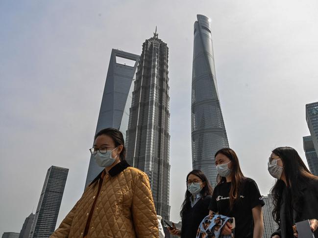 People walk on a pedestrian bridge in the financial district of Shanghai on March 16, 2022. (Photo by Hector RETAMAL / AFP)