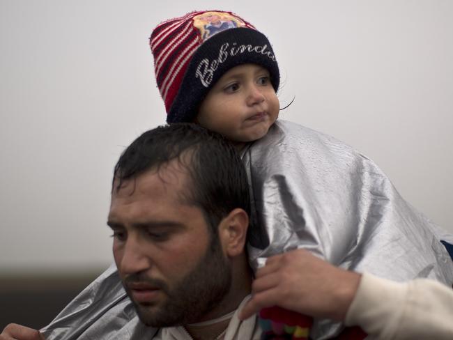 A man carrying his daughter on his shoulder, walks on a railway toward a makeshift camp for asylum seekers in Roszke, southern Hungary, Thursday, Sept. 10, 2015. Leaders of the United Nations refugee agency warned Tuesday that Hungary faces a bigger wave of 42,000 asylum seekers in the next 10 days and will need international help to provide shelter on its border. (AP Photo/Muhammed Muheisen)