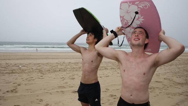 Surfers Paradise streets and beaches were deserted as a wet weather system hovered over the Gold Coast. South Australian holiday-makers including Sam McTaggart and Eddie New from Mt Gambier, try to make the best of a bad lot by heading to the beach despite the rain. Picture Glenn Hampson