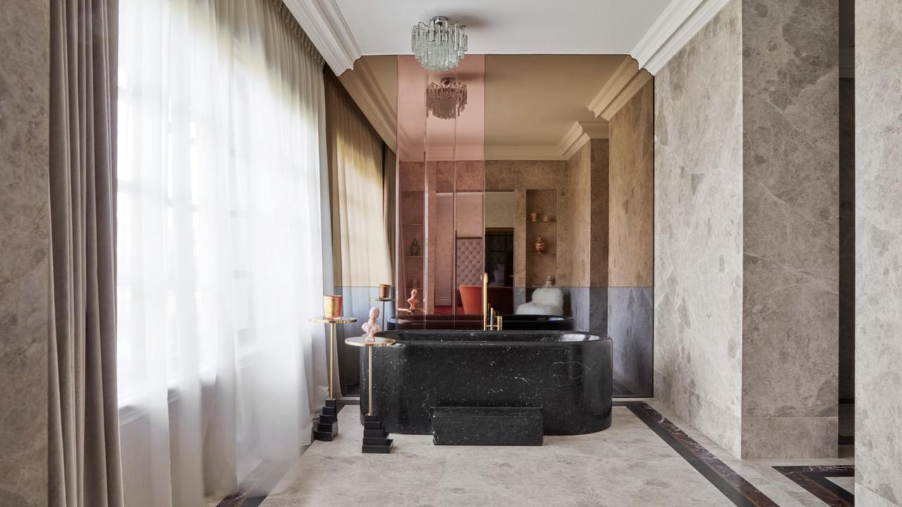 A black bathtub next to a coloured, reflective wall in one of the six bathrooms.