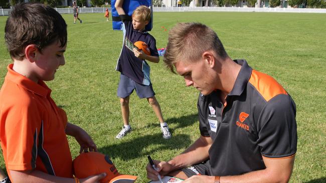 Giants player Adam Tomlinson signs an autograph for a young fan at the Auskick launch.