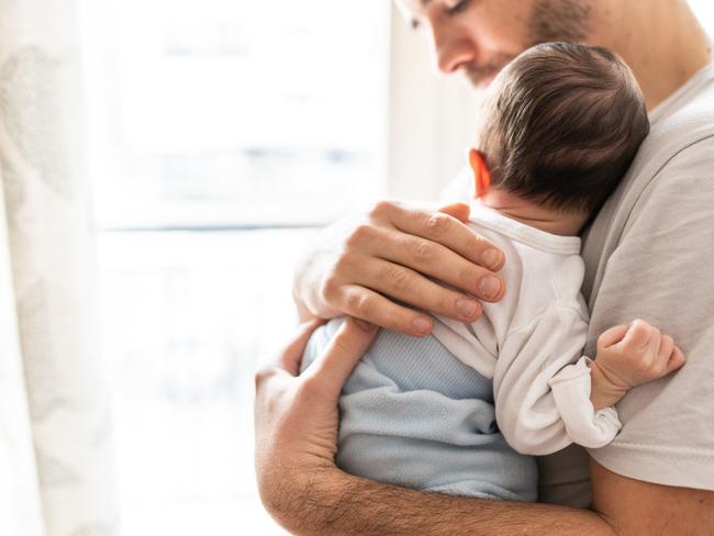 Affectionate love between father and newborn baby, father holding his son in arms in apartment