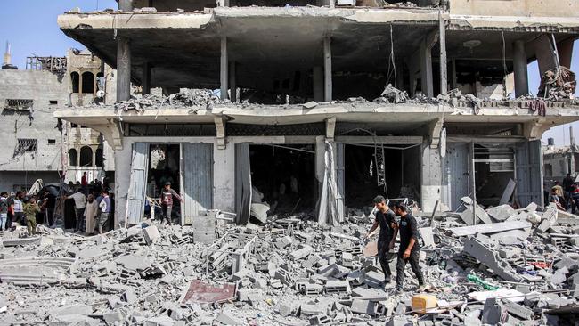 Men walk through rubble following Israeli bombardment on the four-storey Muqat family house in the Zarqa neighbourhood in the north of Gaza City on October 26, 2024 amid the ongoing war in the Palestinian territory between Israel and Hamas. (Photo by Omar AL-QATTAA / AFP)