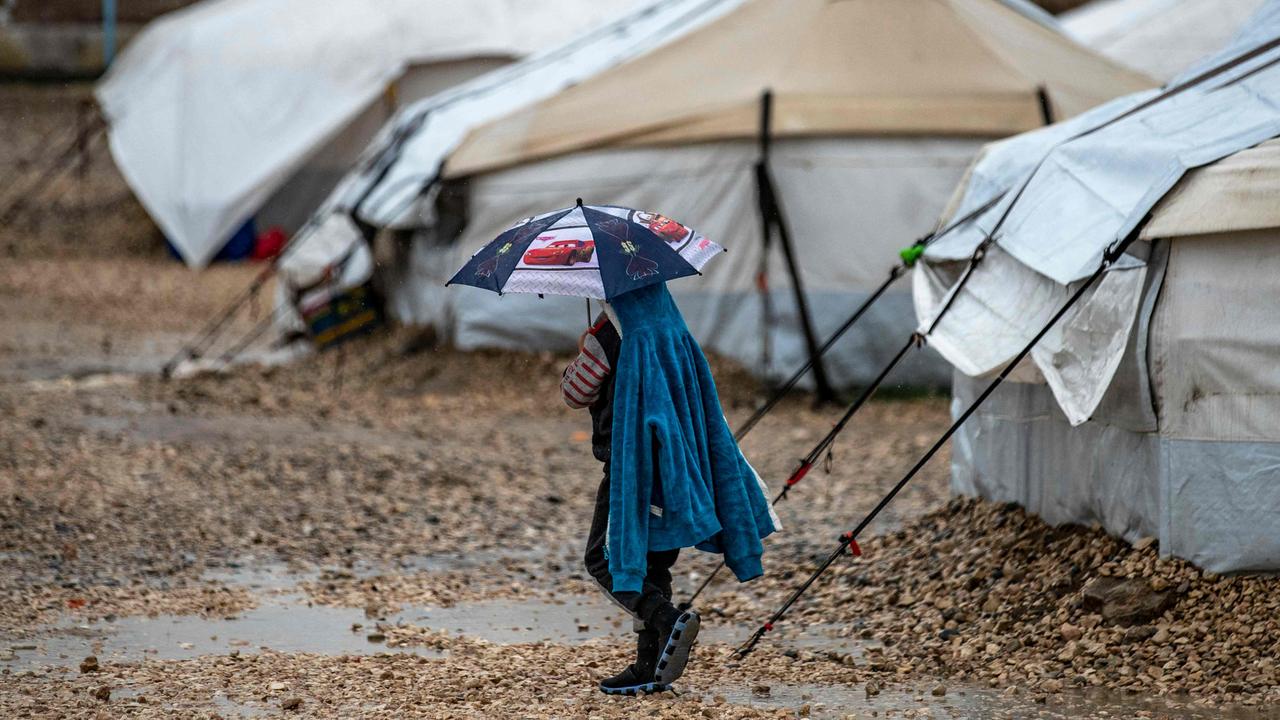 A child walking in the rain at a detention camp in Syria. Picture: Delil Souleiman / AFP