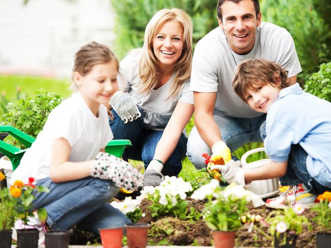 Happy family gardening, planting flowers together. They are looking at the camera. The focus is on the parents.