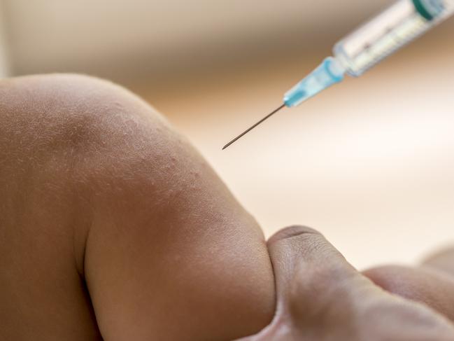 Doctor injecting a young child with a vaccination or antibiotic in a small disposable hypodermic syringe, close up of the kids arm and needle.