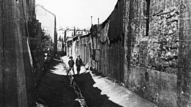 Boys walk along an open sewer drain at rear in Sydney in 1906. Picture: City of Sydney Archives