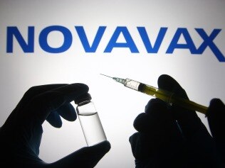 UKRAINE - 2021/04/27: In this photo illustration, silhouette of hands in medical gloves hold a medical syringe and a vial in front of Novavax logo. (Photo Illustration by Pavlo Gonchar/SOPA Images/LightRocket via Getty Images)