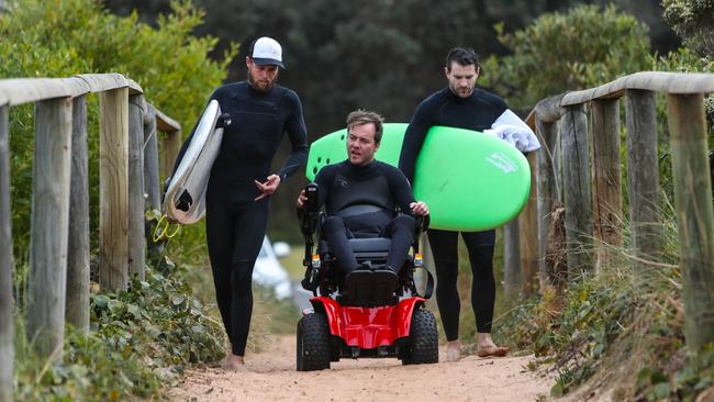 Mark Leslie heads to the beach for a surf with therapist Seb van Veenendaal (right) and is carer Anthony Robertson. Picture: Julian Andrews/AAP