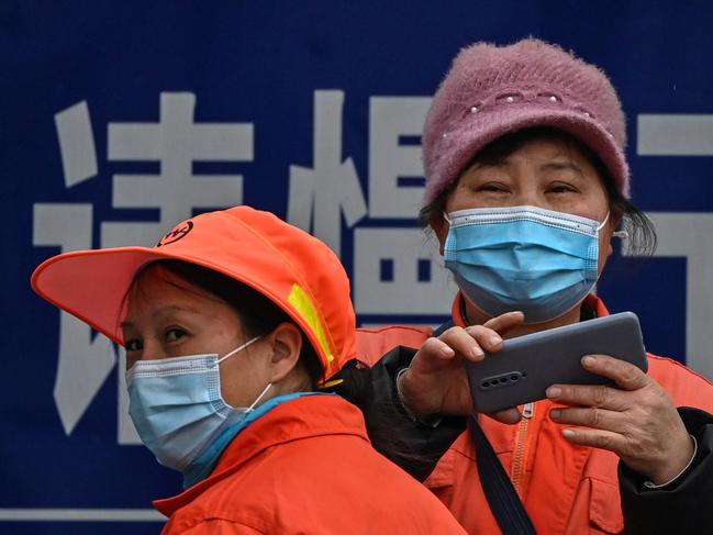 A woman takes photos in front of the Jiangxinyuan community centre where members of the WHO team investigating the origins of coronavirus. Picture: AFP