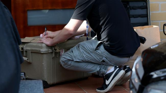 A detective makes notes as the property is searched in Auburn. Picture: Jonathan Ng