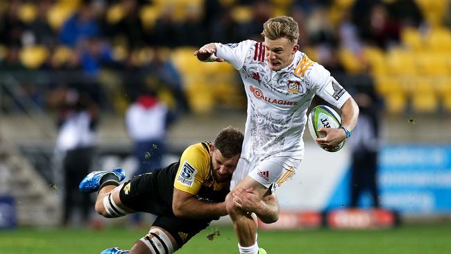 Damian McKenzie of the Chiefs is tackled by Callum Gibbins of the Hurricanes.