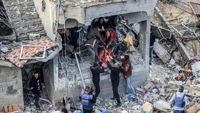 Men recover the body of a victim killed in the aftermath of an overnight Israeli strike at al-Maghazi refugee camp on December 25. Picture: Mahmud Hams/AFP