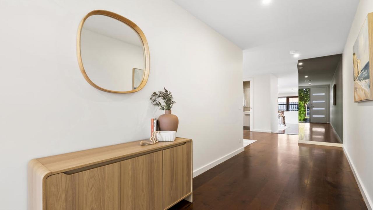 A wide timber hallway sets the tone with warmth, flow and clean architectural lines from the outset.