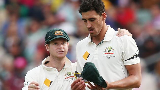 Mitchell Starc of Australia reacts in pain as he is comforted by Steve Smith.