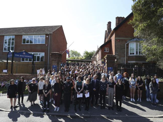 Colleagues and pupils of teacher James Furlong stand together to take part in a period of silence at the Holt School, in Wokingham, England. Picture: AP