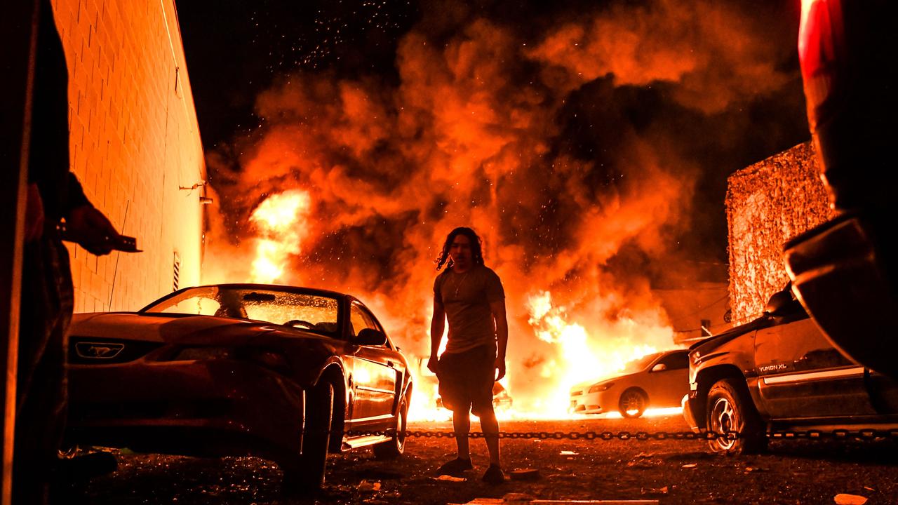 A man tries to tow away a car as a local parking garage is set ablaze in Minneapolis. Picture: Chandan Khanna/AFP