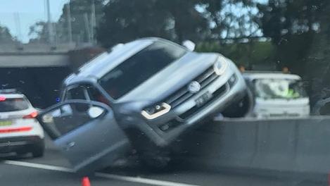A Volkswagen ute is pictured mounted on a concrete divider on the M5 at Padstow after its driver went the wrong way. Picture: Ben Pike