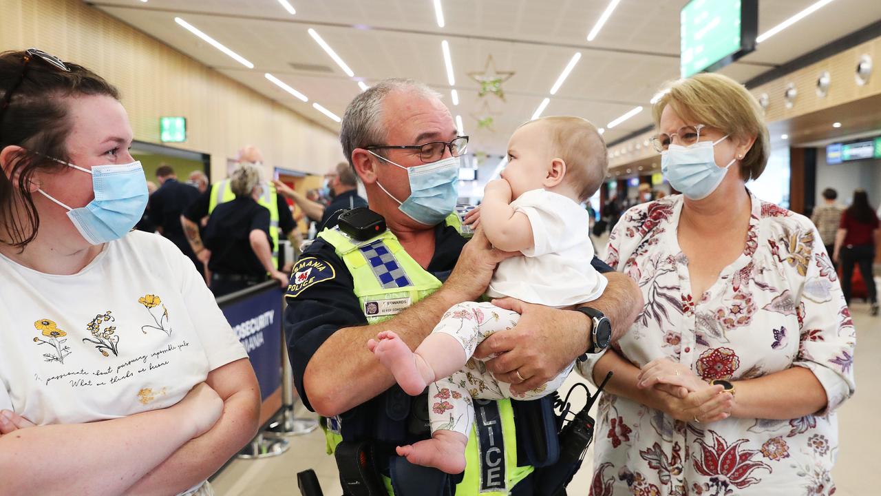 Tasmania Police Senior Constable Paul Edwards who was working at the airport on day 1 of border reopening reunited with granddaughter Isla 7 months from Newcastle who have been separated since she was 4 weeks old. Mum Lauren Edwards and grandmother Debbie Edwards look on. Picture: Nikki Davis-Jones