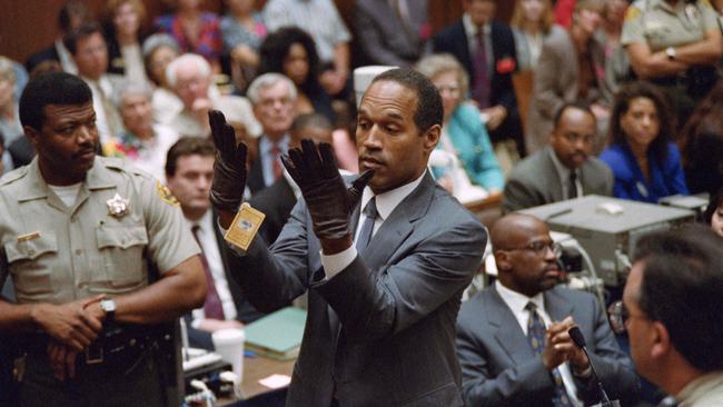 OJ Simpson (C), looks at a new pair of Aris extra-large gloves which the prosecutors had him put on for the jur during his trial. Picture: AFP.