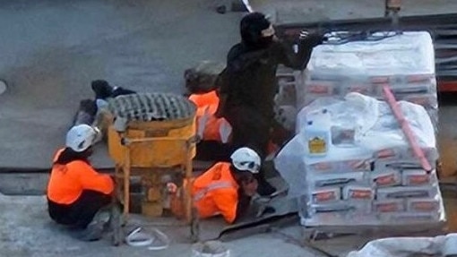 Construction workers hid behind pallets as police attempted to protect them. Picture: Stuff.co.nz