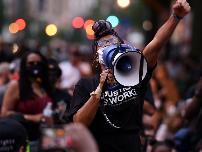 A protester speaks into a bullhorn as people kneel and hold their hands up in front of Lafayette park near the White House to protest the death of George Floyd. Picture: AFP